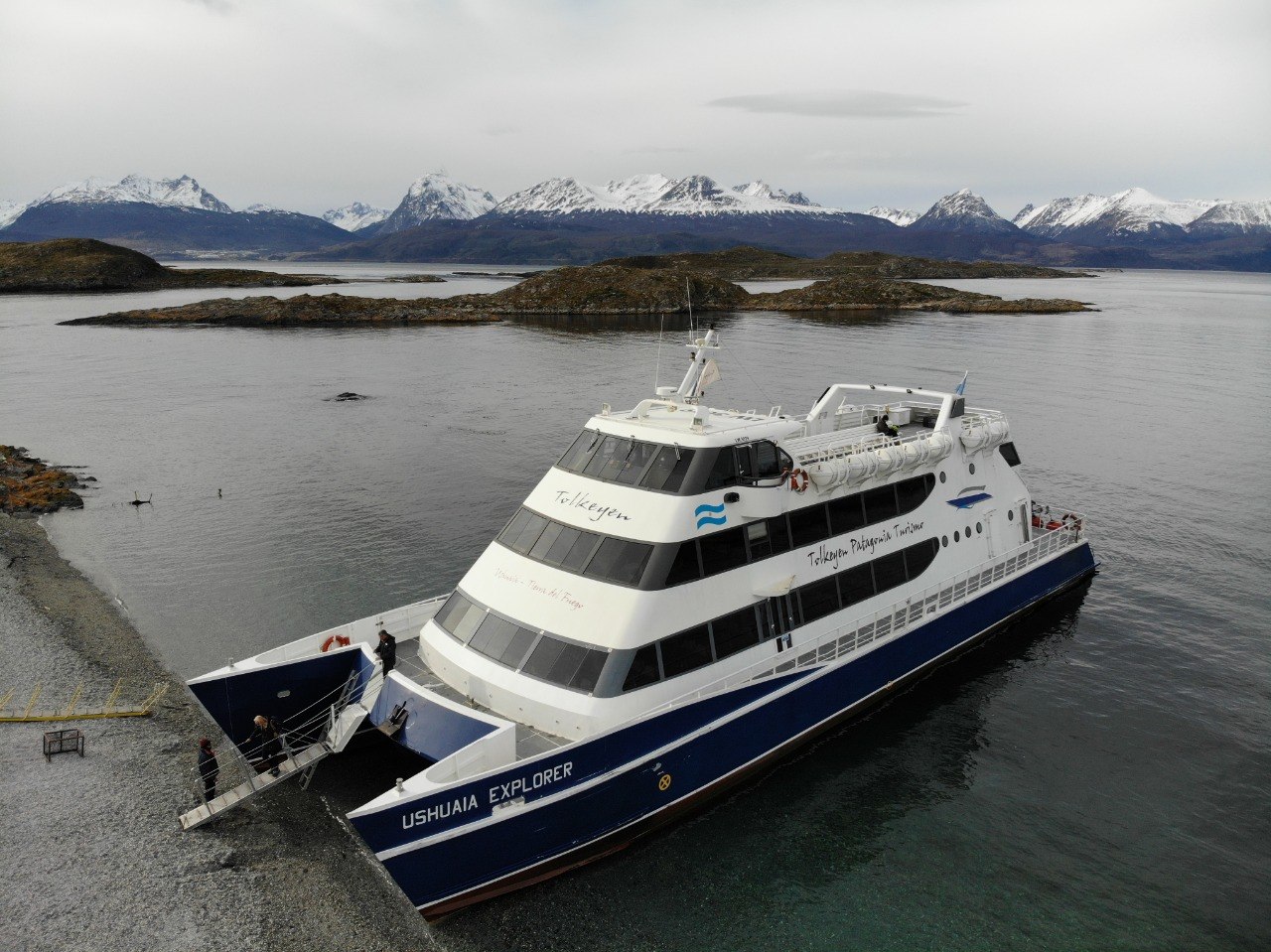 Catamarán durante un desembarco en el Canal Beagle con montañas de fondo